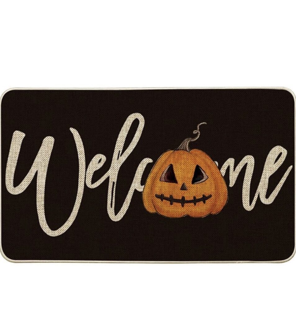 Elegant Halloween front porch with a black door, glowing wreath, black lanterns, orange and white pumpkins, mums, layered doormats, bats, lighted branches, and warm candlelight.